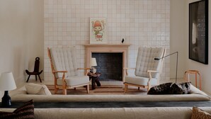 Un salon avec deux fauteuils, un canapé, une cheminée et un tableau encadré au mur.