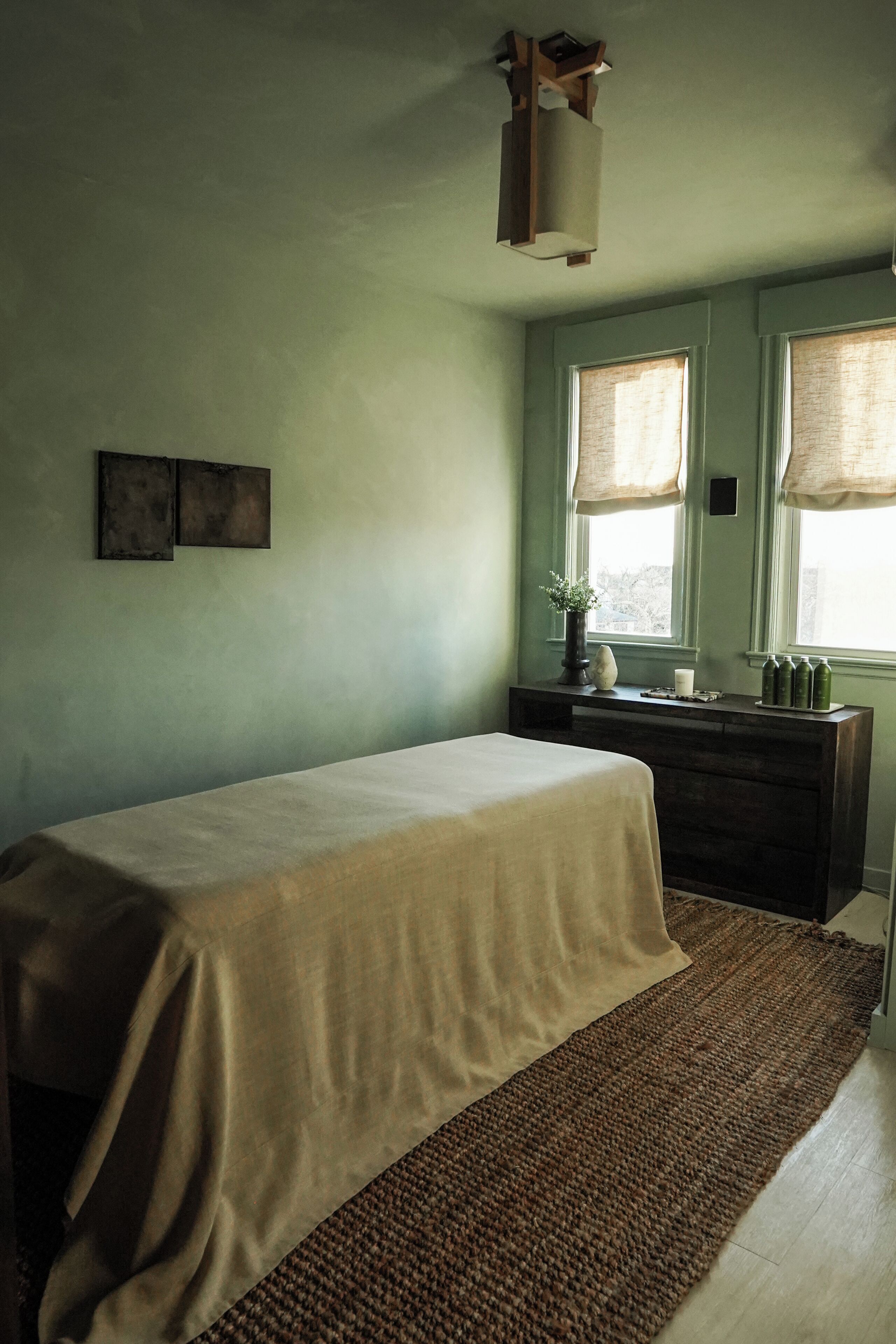 A bedroom with a bed, dresser, and windows.