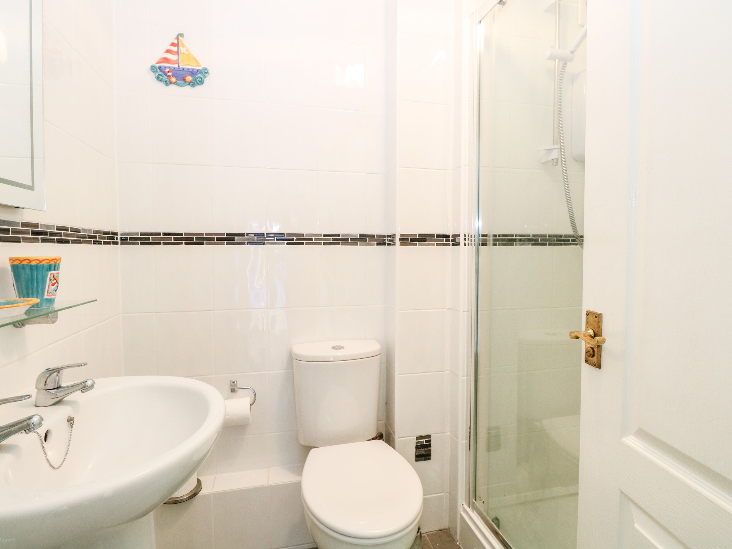 Ein Badezimmer mit weißem Waschbecken, Toilette und Duschkabine.