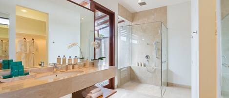 A modern bathroom with a large mirror, a glass shower enclosure, and a vanity with a beige countertop.