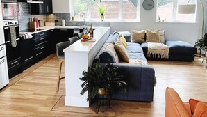 Una cocina moderna con una isla central, un área de comedor con un sofá y un gran ventanal que proporciona luz natural.