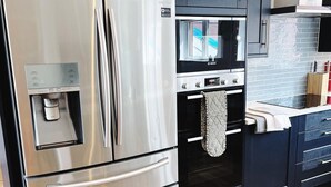Una cocina moderna con un refrigerador de acero inoxidable, un horno Bosch y armarios oscuros.