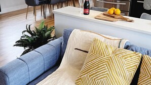 Una cocina moderna con una isla central, electrodomésticos de acero inoxidable y un comedor con sillas y una mesa.