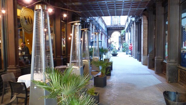 Un couloir doté d’un sol carrelé, de plantes en pot et de lampes suspendues.