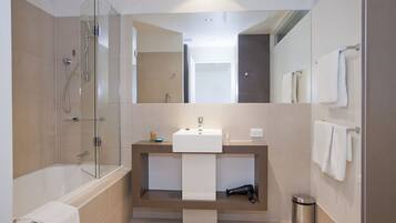 A modern bathroom with a glass shower enclosure, a standalone bathtub, a sink with a towel, and a mirror.