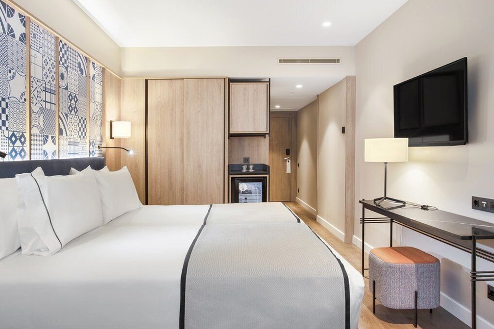 Ein Hotelzimmer mit einem großen Bett, einem Schreibtisch, einem Fernseher und einer Minibar.