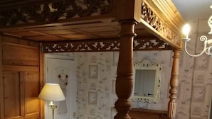A bedroom with wooden paneling, a bed with white bedding, a floor lamp, and a mirror with a decorative frame. - Tranquil Retreat - 3 Bedroom House With hot tub (Torquay)