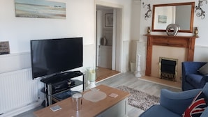A living room with a television, a fireplace, and a sofa. - Tranquil Retreat - 3 Bedroom House With hot tub (Torquay)