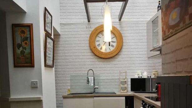 A kitchen with a round clock, a sink, and modern appliances. - Tranquil Retreat - 3 Bedroom House With hot tub (Torquay)