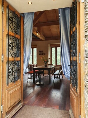 A wooden interior with a dining table, chairs, and curtains.