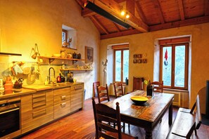 A kitchen with wooden cabinets, a dining table, chairs, and a window with a view.