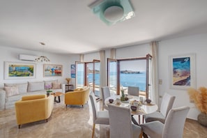 Un salon moderne comprenant un canapé, des fauteuils, une table à manger et des œuvres d’art.