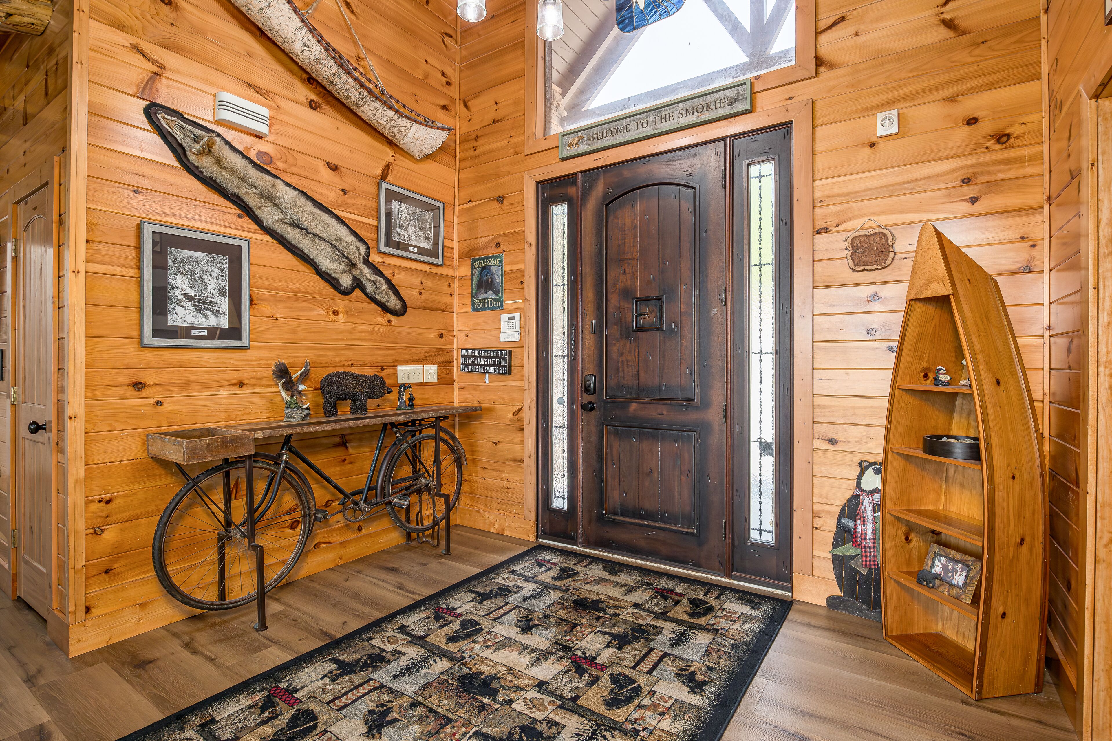 A wooden interior with a bicycle, a welcome sign, and a rustic door.