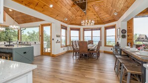 A spacious kitchen with wooden floors, a central island, and large windows offering views of the outdoors. - Five Bears Mountain View Lodge - Private Mtn Views -  Ultimate Luxury Cabin (Sevierville)
