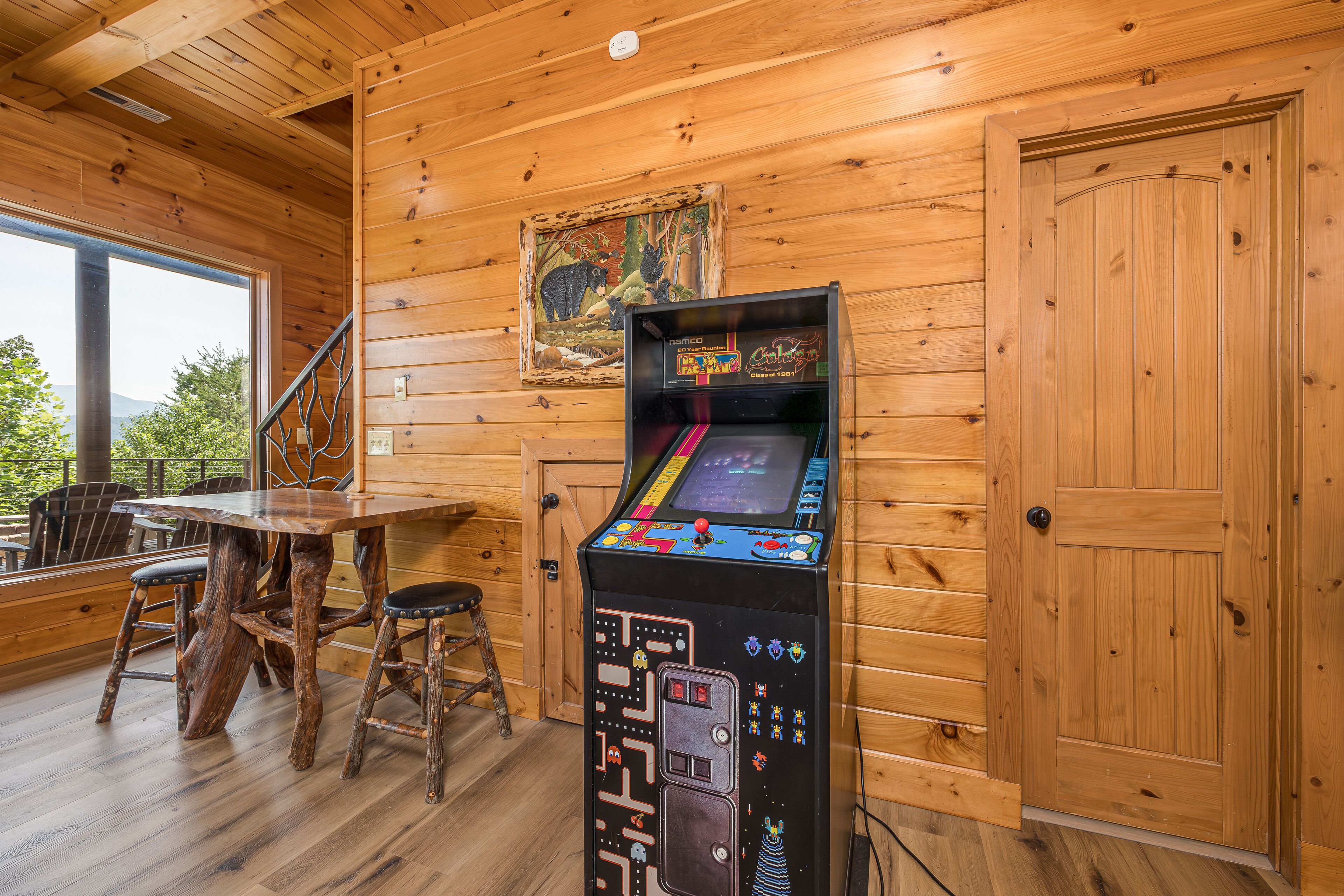 Un intérieur en bois avec une table et des chaises en bois, une console de jeux et une porte.