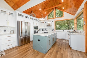 Enjoy cooking in this well-equipped kitchen with a central island, ample counter space, and a large window offering a view of the surrounding greenery.