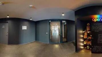 A corridor with doors leading to rooms, a reception area, and a store with a sign that says 'open'.