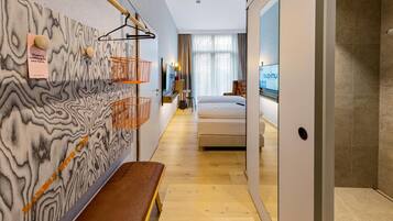 Quarto de hotel moderno com parede de mármore, um banco de madeira, cama, televisão e banheiro com chuveiro.