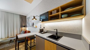 Una cocina moderna con microondas integrado, un lavamanos y estantes de madera arriba.