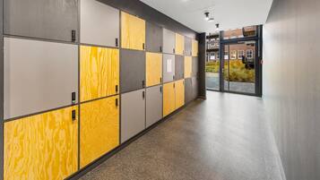 A hallway with lockers, a glass door entrance, and a view of a building with windows.