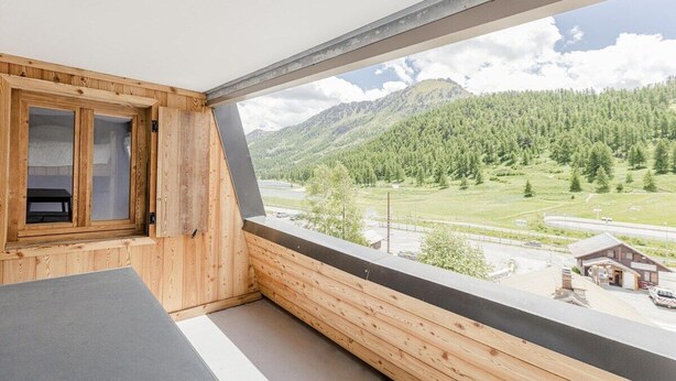 A wooden balcony with a view of a mountainous landscape and a small building in the distance. - Apartment Véronique, front of village location (Montgenevre)