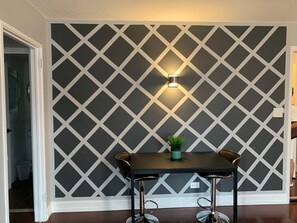 Simple, modern space with a geometric patterned wall, small table, and single chair.