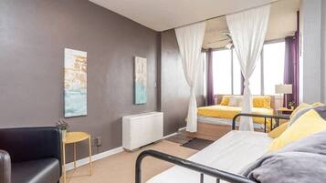 A bedroom with a bed, a bedside table, a chair, and a window with curtains.