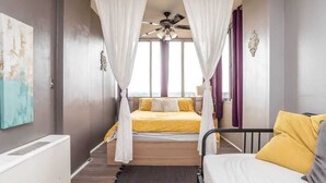 A bedroom with a bed, a bedside table, a ceiling fan, and a window with curtains. - Spacious 1 Bed Condo with City View (Atlanta)