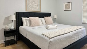 A bedroom with a bed, two bedside tables, a ceiling fan, and two wall-mounted artworks. - Condo in the Heart Atlanta w/ Private Balcony (Atlanta)