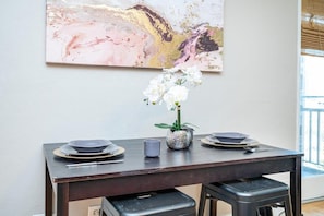 Une table à manger avec des assiettes, un vase rempli de fleurs et un tableau accroché au mur.