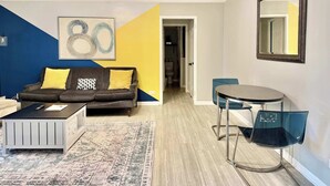 Una sala de estar moderna con un sofá, una mesa de centro y un comedor con una silla y una mesa.