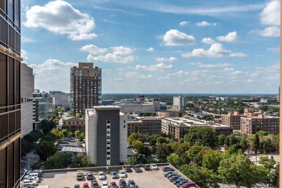 Une vue urbaine comprenant un parking, des immeubles et un ciel dégagé.