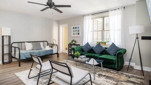A modern living room with a bed, green sofa, and a coffee table.