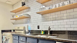 A kitchen with white subway tiles, wooden shelves, a stove, and a dishwasher. - Stunning 22nd-Floor Condo with City Views (Atlanta)