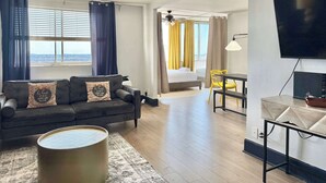 A modern living room with a sofa, a coffee table, a TV, and a dining area. - Stunning 22nd-Floor Condo with City Views (Atlanta)