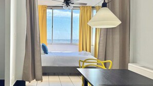 A hotel room with a bed, a desk, a chair, a ceiling fan, and a window with curtains. - Stunning 22nd-Floor Condo with City Views (Atlanta)