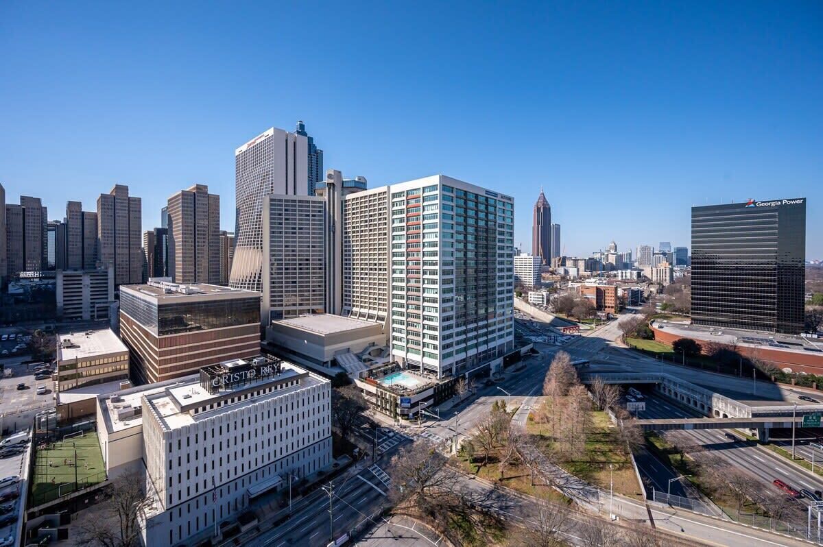 A cityscape with modern high-rise buildings, including a prominent white building with a grid-like facade and a large glass structure.