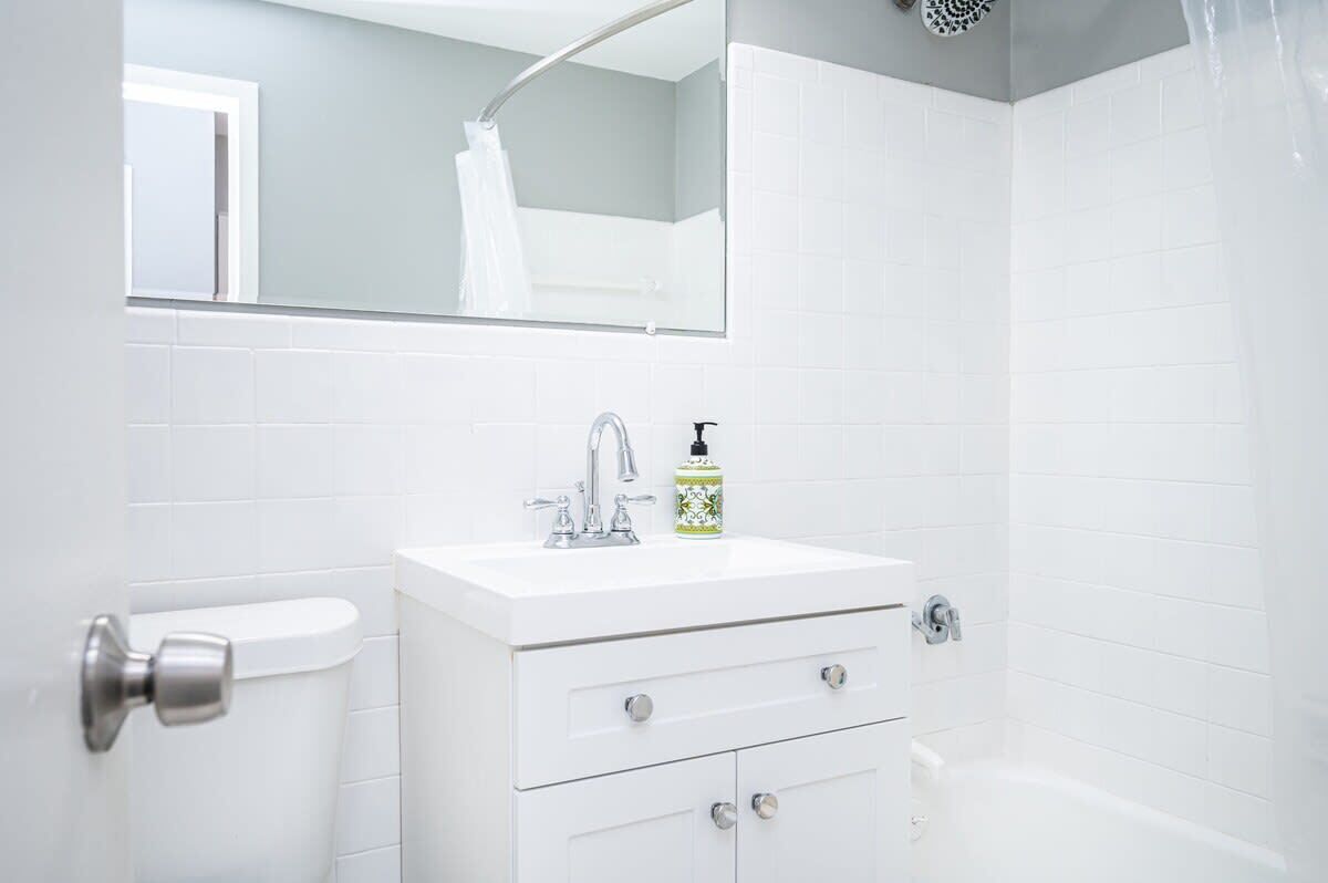 Une salle de bain avec un lavabo blanc, un miroir et une douche.
