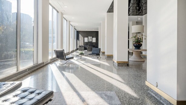 A spacious hallway with large windows, a seating area with a sofa and chairs, and a decorative table with a plant. - Downtown Atlanta Condo with City View (Atlanta)