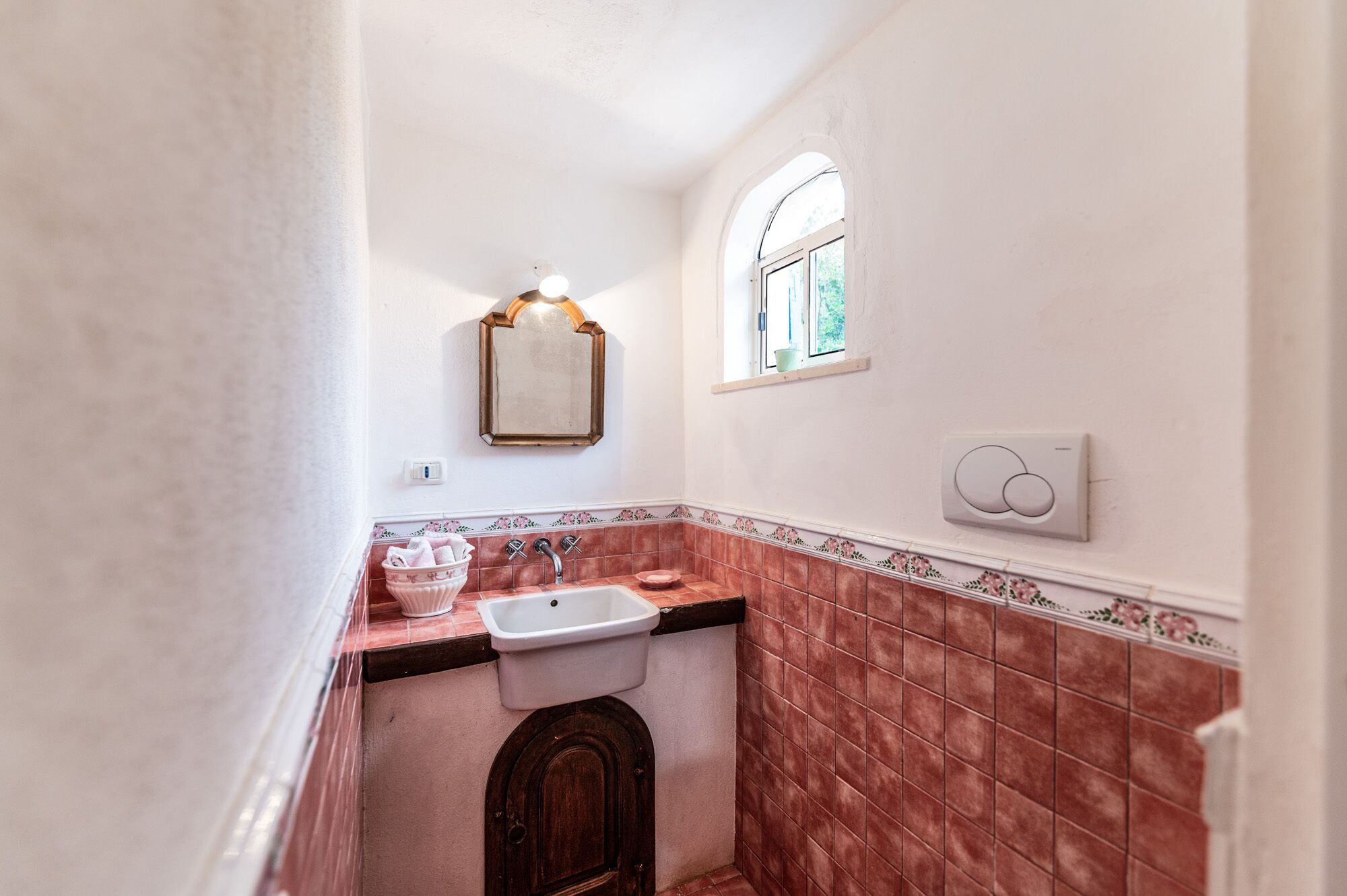 Ein schmales Badezimmer mit Waschbecken, Spiegel und Fenster.