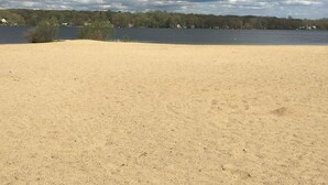 Hiekkainen ranta, jonka taustalla on järvi ja puita.