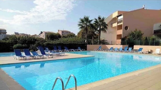 En pool med solstolar och en kakelbeklädd poolterrass.