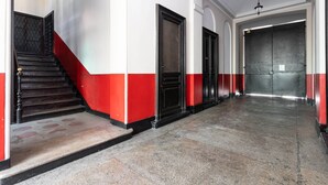 Ein Flur mit Treppe, Wänden in Rot und Schwarz und einem Marmorboden.
