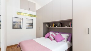 Ein Schlafzimmer mit einem Bett, einem Bücherregal und zwei gerahmten Bildern an der Wand.