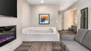 A modern bathroom with a large bathtub, a flat-screen TV, and a fireplace. - Amsterdam Inn & Suites, an Ascend Collection Hotel (Florenceville-Bristol)