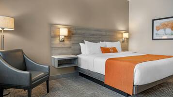 A hotel room with a bed, a chair, a nightstand, and a lamp.