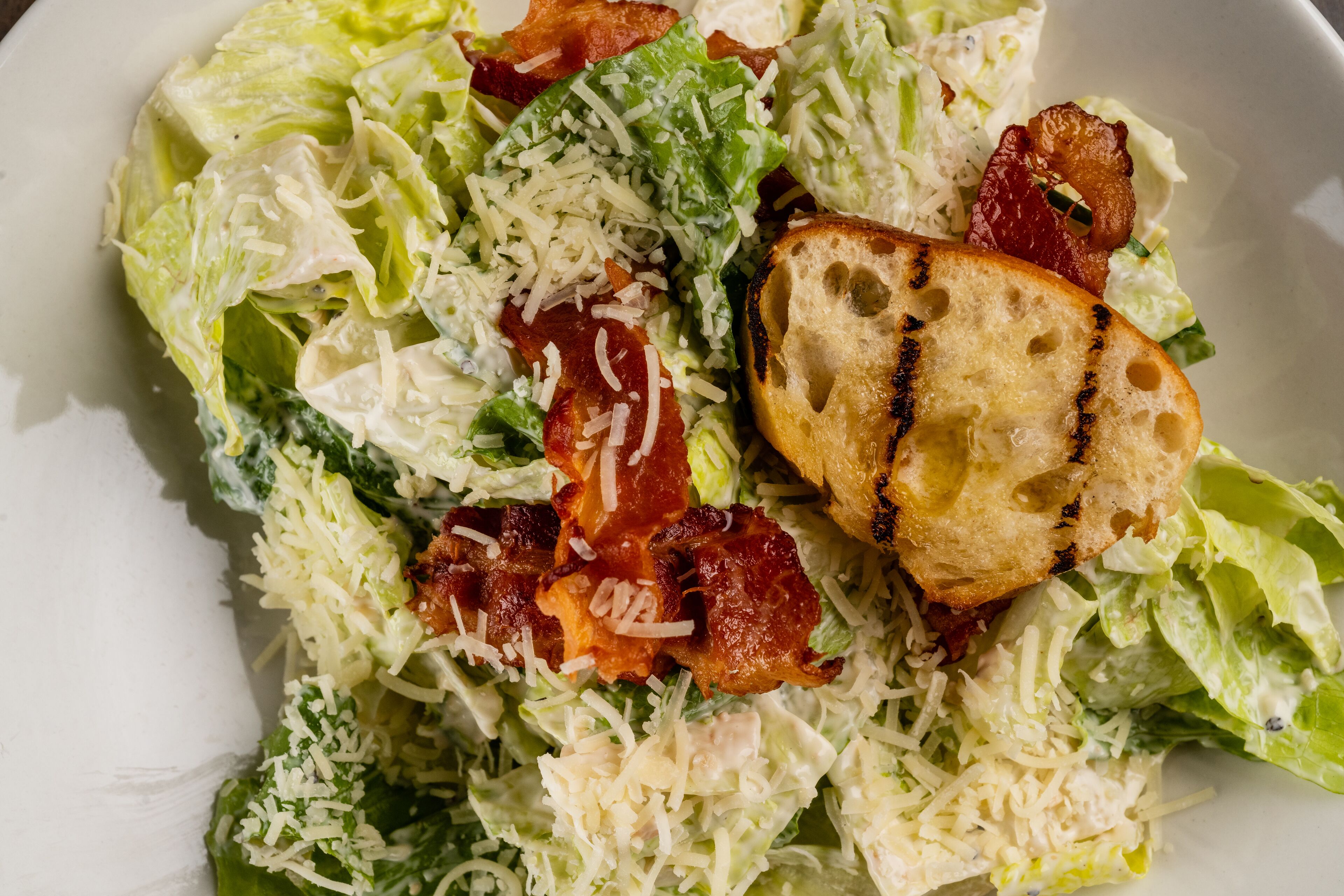 Une salade composée de laitue, de fromage et de lardons.