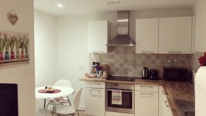 Une cuisine compacte équipée d’un four à micro-ondes, d’un four traditionnel et d’une petite table à manger avec des chaises.