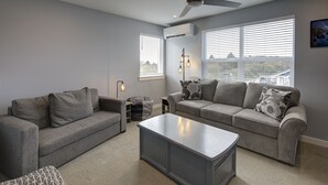 A modern living room with grey sofas, a coffee table, and a ceiling fan. - The Sanctuary - Oyhut Bay Seaside Village (Ocean Shores)
