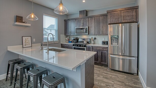 A modern kitchen with a large island, stainless steel appliances, and bar stools. - The Sanctuary - Oyhut Bay Seaside Village (Ocean Shores)
